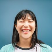 Portrait of young Asian girl smiling at camera - Happy Chinese woman having fun posing against blue background - Teen, trendy, millennial generation and youth people lifestyle